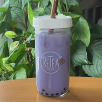 3 tablespoons of taro milk tea powder poured into clear glass reusable Retea cup, added one tablespoon of lactose-free creamer, added 250ml of hot water, stir until well mixed, add 250ml of ice, put on non-leak plastic lid and shake until milk tea cools, add cooked tapioca, stir with rainbow stainless steel boba straw