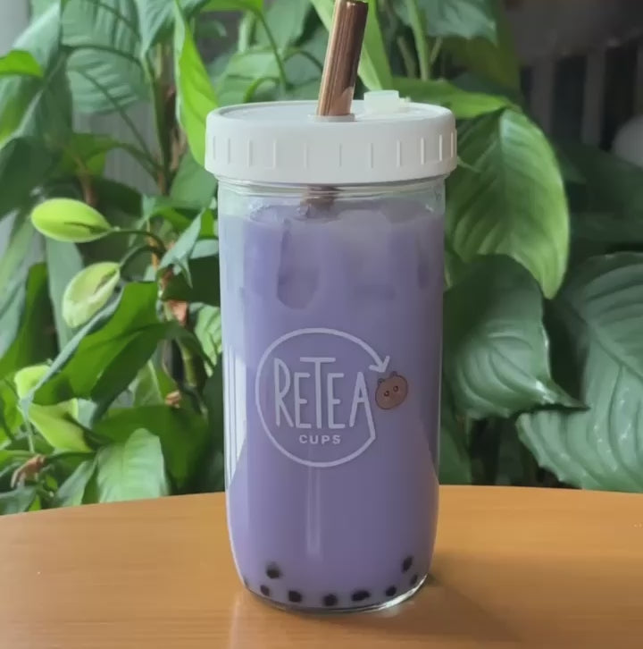 3 tablespoons of taro milk tea powder poured into clear glass reusable Retea cup, added one tablespoon of lactose-free creamer, added 250ml of hot water, stir until well mixed, add 250ml of ice, put on non-leak plastic lid and shake until milk tea cools, add cooked tapioca, stir with rainbow stainless steel boba straw